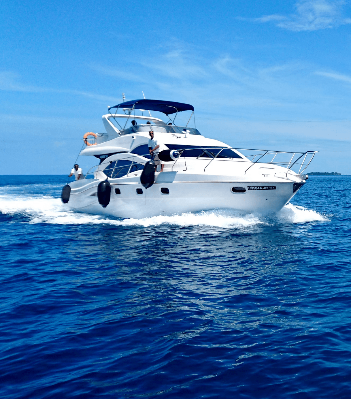 White luxury motor yacht cruising through deep blue ocean water under a clear blue sky.