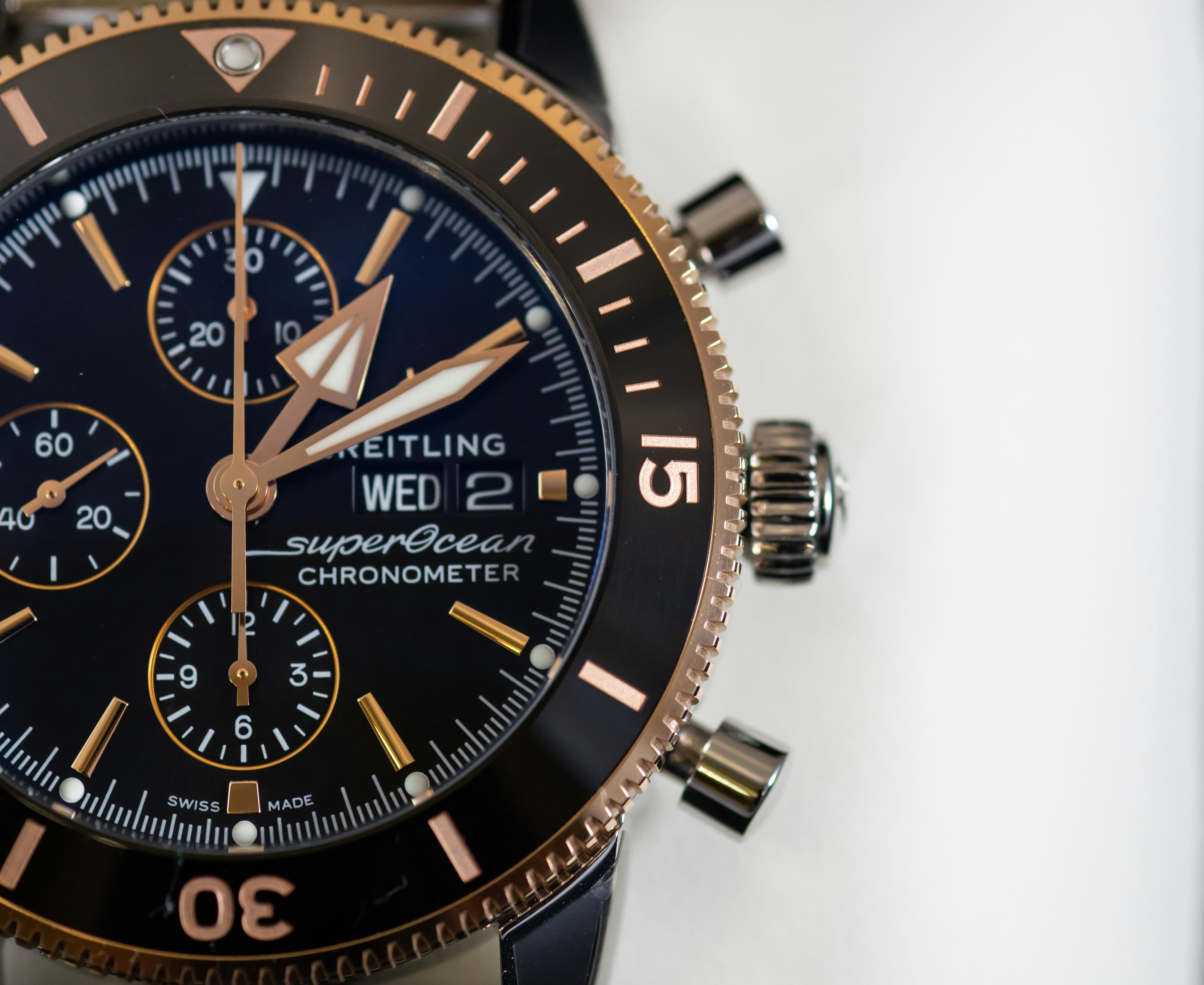 Close-up of a Breitling Superocean chronograph watch with black dial and rose gold accents.